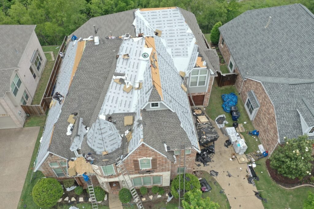 Aerial view of Roofing Giant crew replacing the roof of a two-story brick home