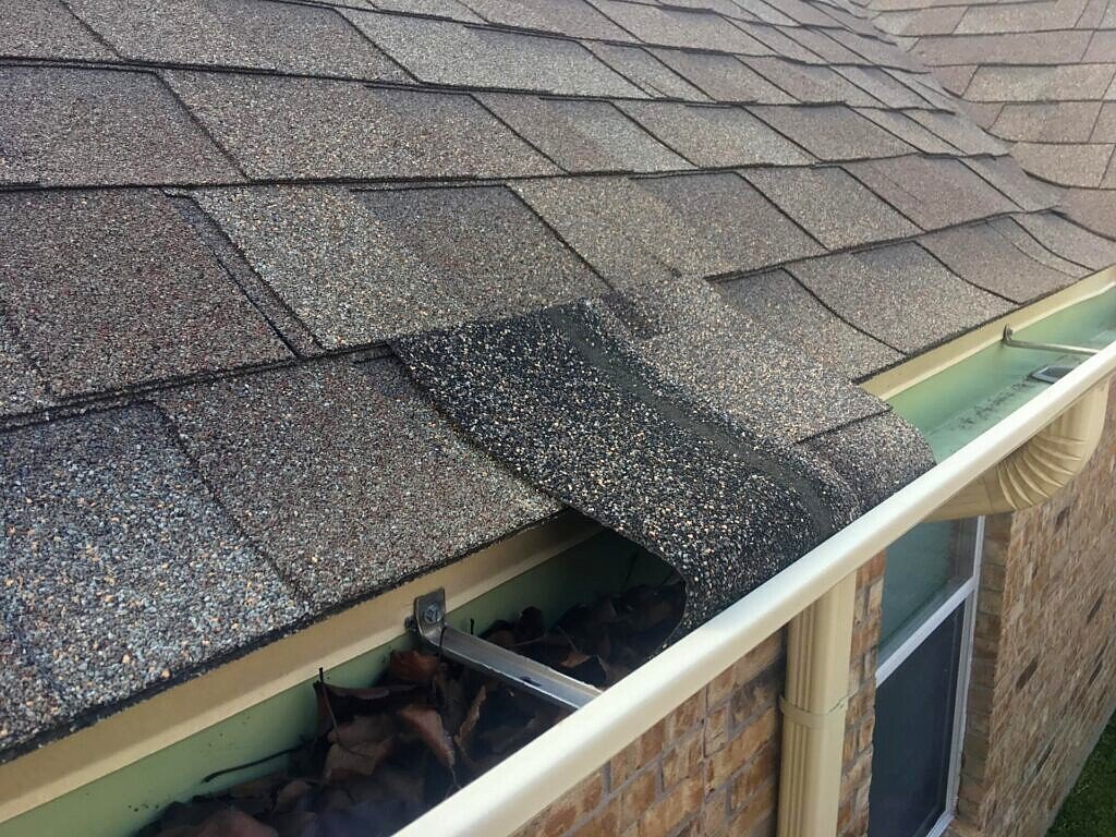 November 2017. Existing shingles and debris in the gutter at the eave.