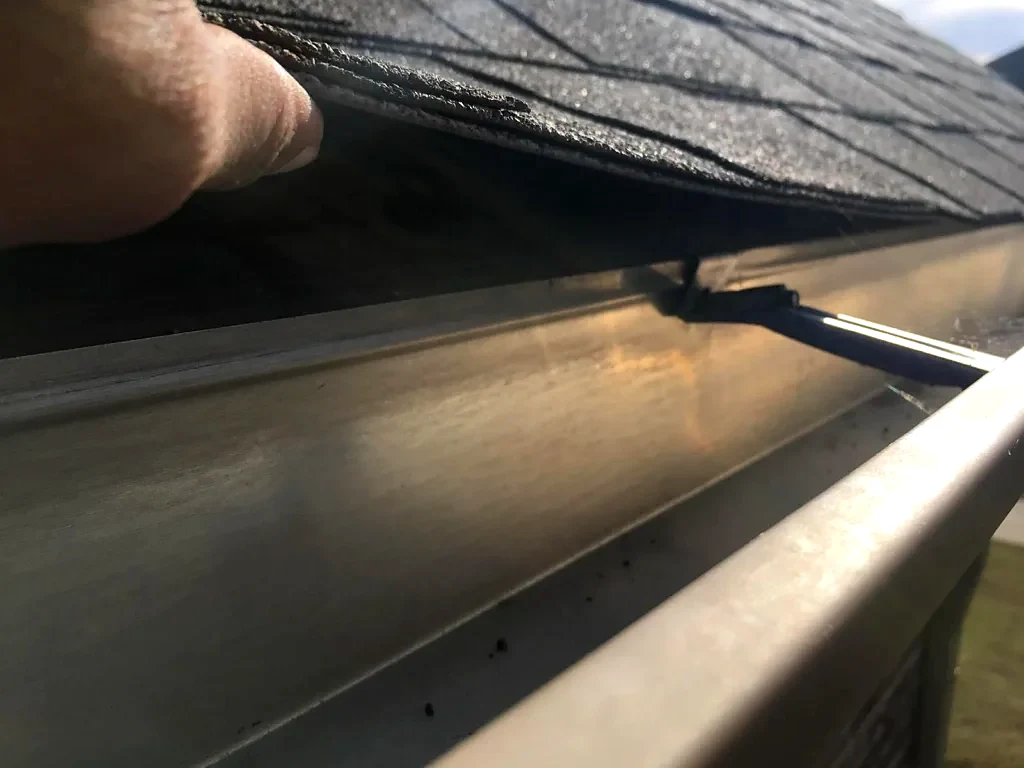 Shingle edge and gutter inspected before work.