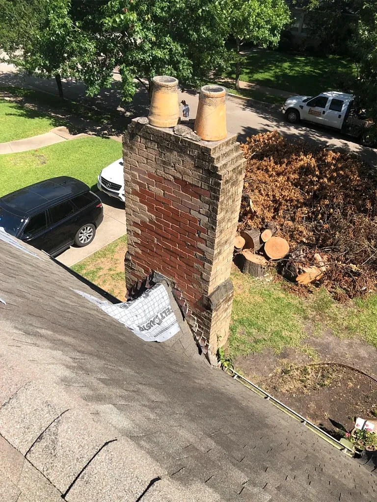 Masonry chimney and adjoining shingles before work.