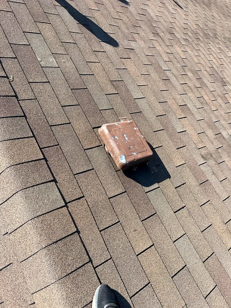 Low-profile vent and surrounding shingles during inspection.