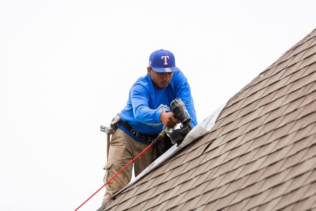 Roofing Giant roofer installing shingles with a pneumatic nail gun