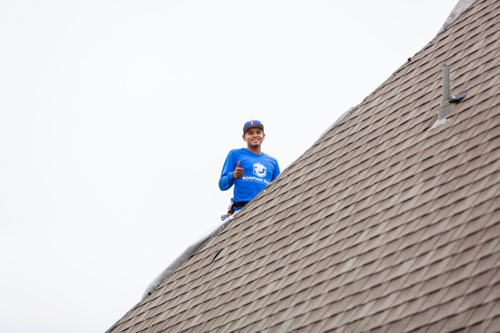 Roofing Giant roofer working at the ridge of an architectural shingle roof in North Texas