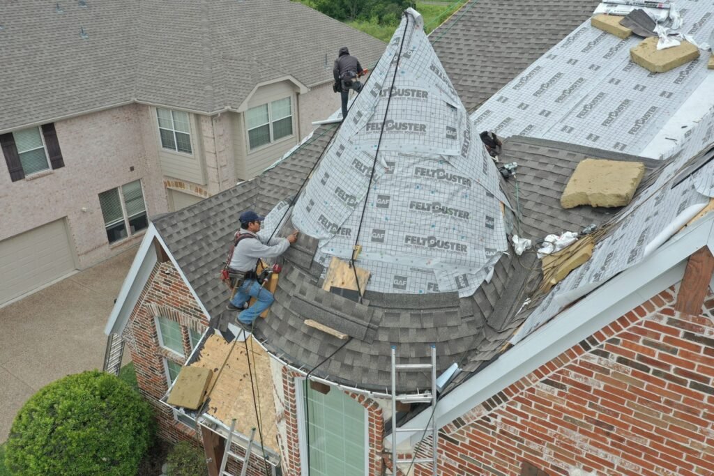 Roofing Giant roofers installing underlayment on a steep turret roof section