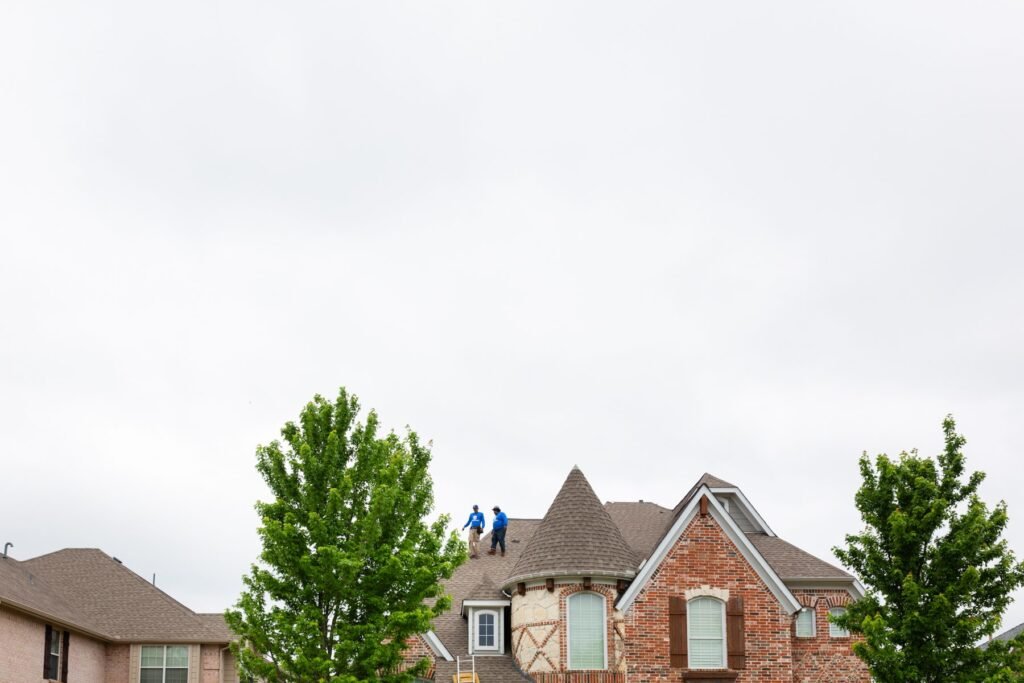 Roofing Giant team standing with the company trucks in front of a two-story brick home