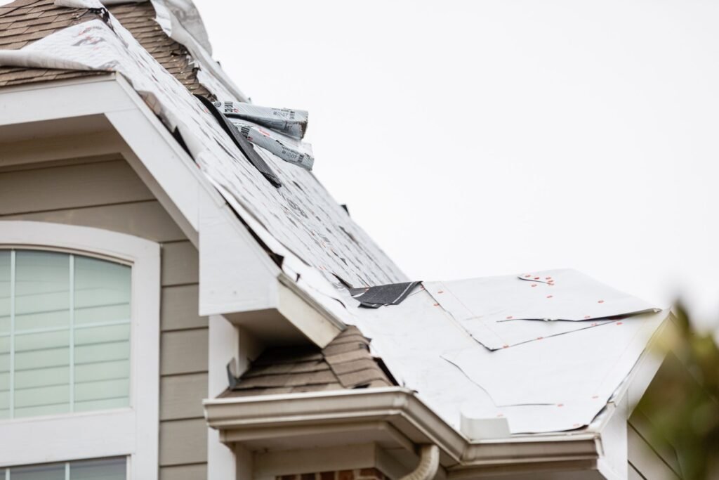 Lifted and creased shingles on a roof slope after wind damage